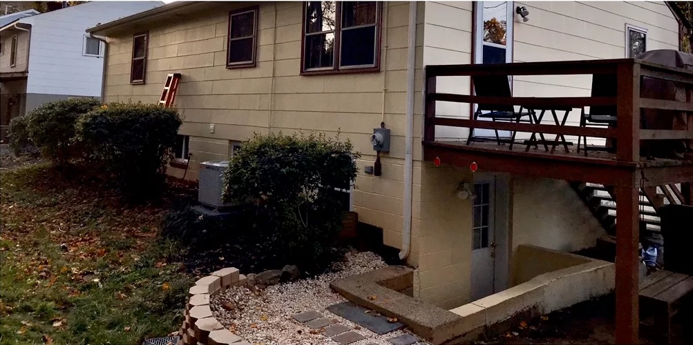 Residential home with tan siding, gravel landscaping, and red metal deck structure