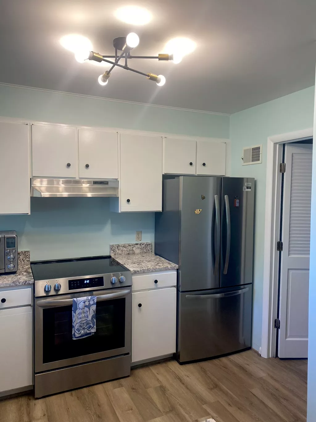 Modern kitchen with white cabinets, stainless steel appliances, granite countertops, and blue backsplash
