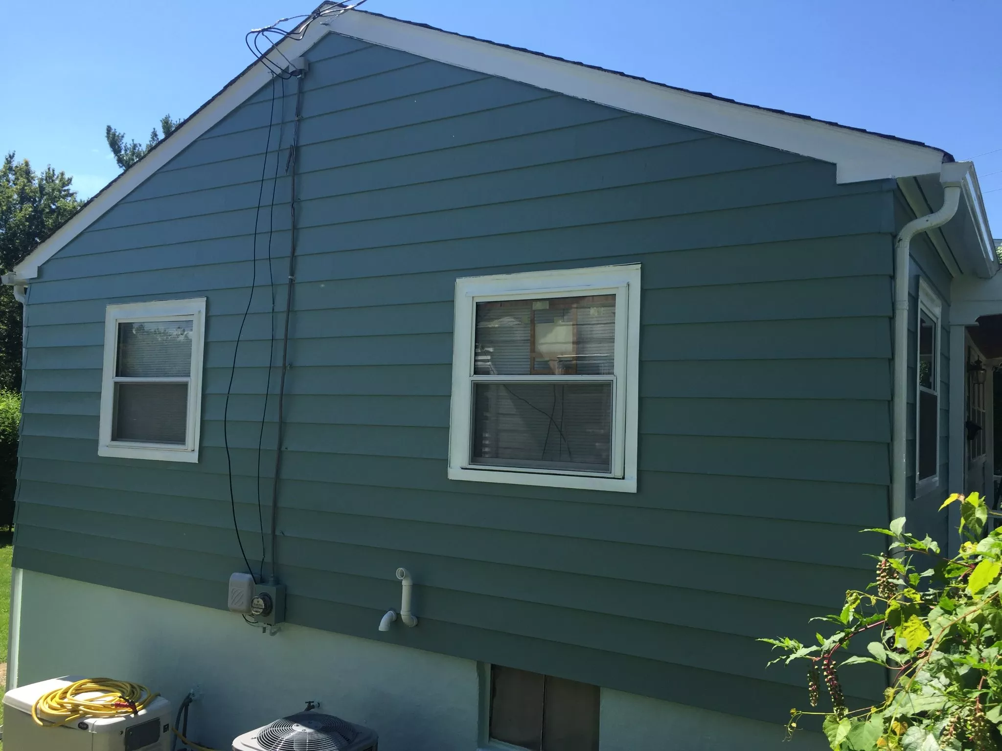 Green and white mobile home with two windows and side entrance door