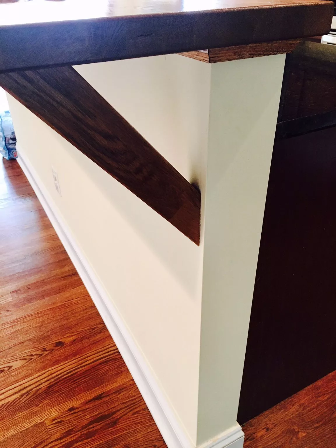 Dark wood stair railing with cream-colored wall and wooden handrail on hardwood floor