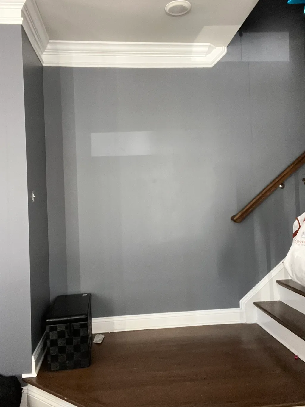 Empty hallway with gray walls, white trim, wooden handrail, and dark hardwood flooring
