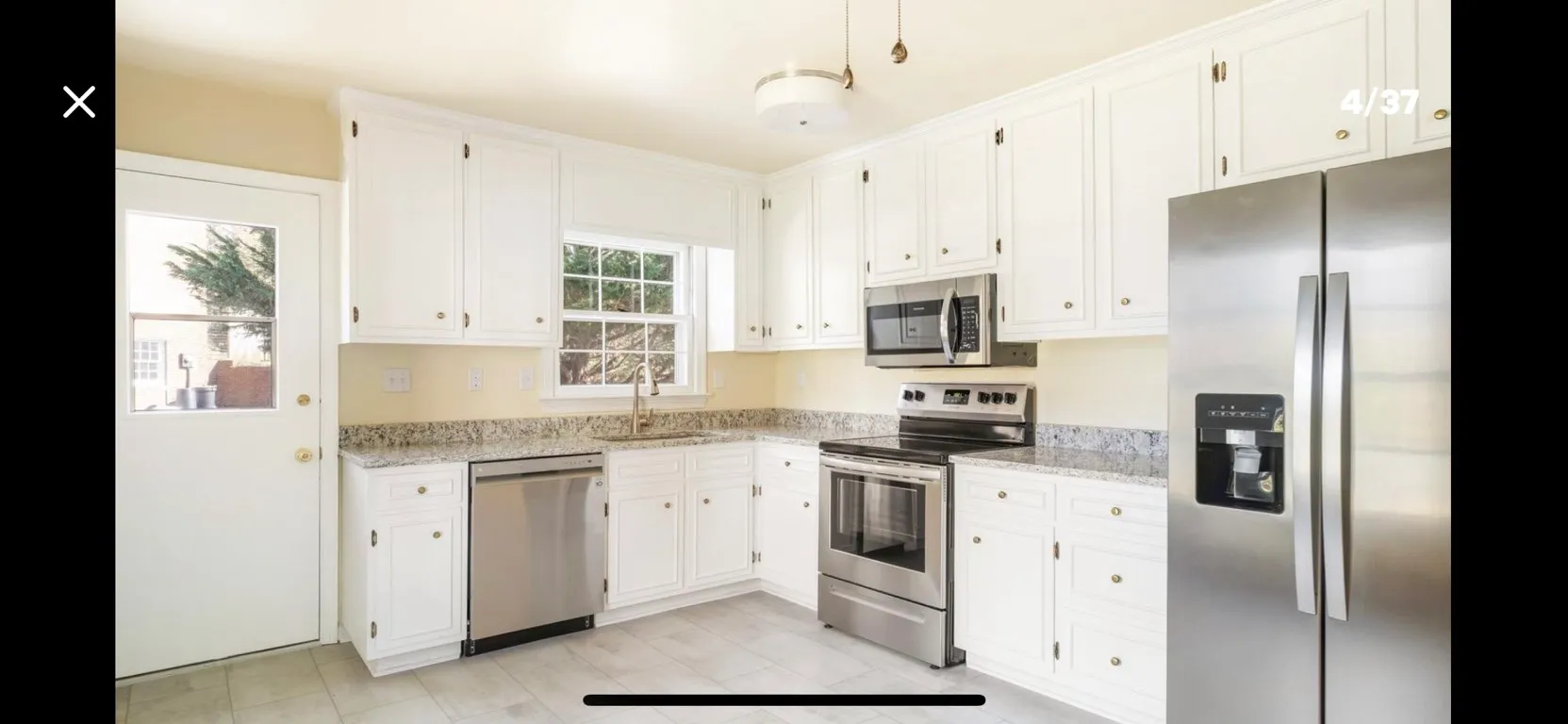 Modern white kitchen with stainless steel appliances and granite countertops